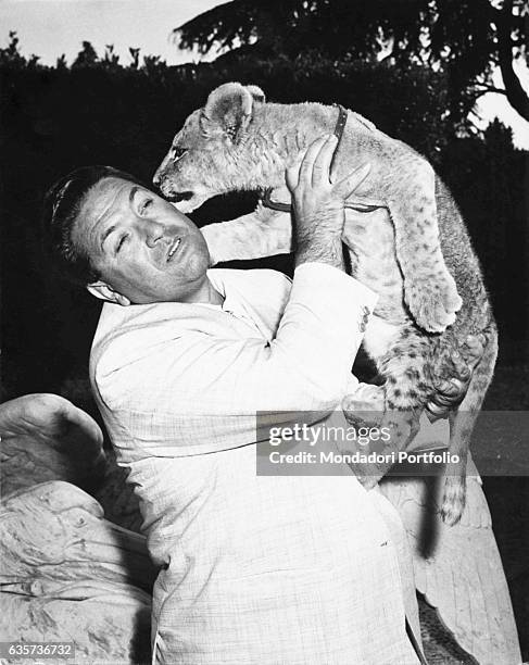 Italian TV host Angelo Lombardi holding a lion cub in the TV show L'amico degli animali. 1960