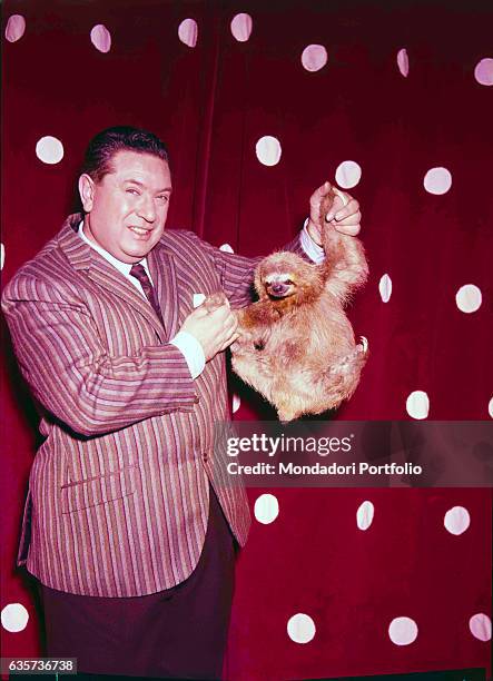 Italian TV host Angelo Lombardi holding a sloth in the TV show L'amico degli animali. 1960