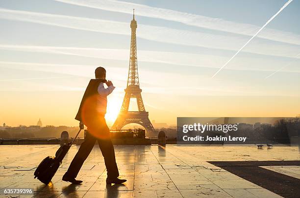 homme d’affaires de voyage marchant avec valise à la tour eiffel à paris - eiffel tower sunrise photos et images de collection