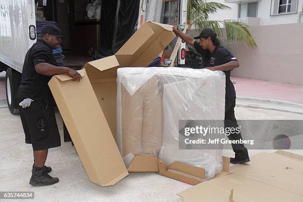 Delivery men removing the packaging from a recliner chair.