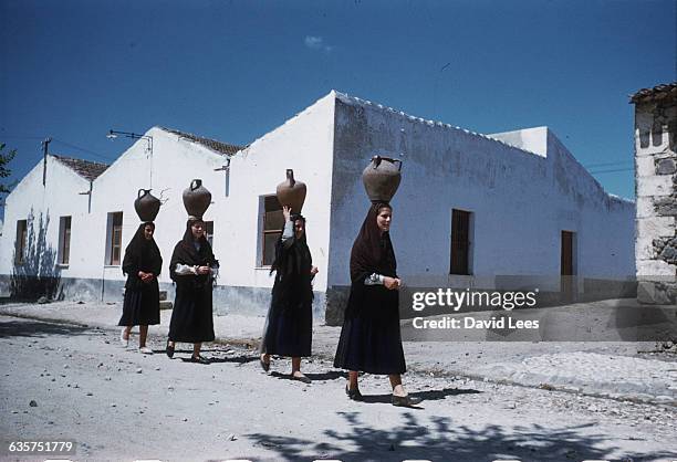 Four girls from the village of Ploaghe carry water pitchers balanced on their heads. | Location: Ploaghe, Sardinia.