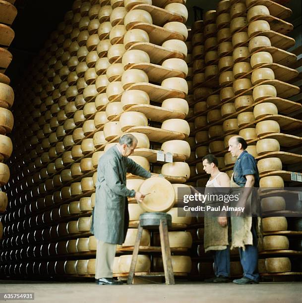 Inspectors look over a cheese wheel in a warehouse, which is the largest storage facility for Parmesan cheese in Parma, Italy.
