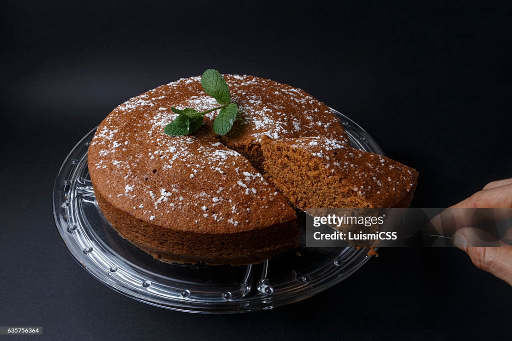 Frau serviert einen Schokoladenkuchen mit einem Spachtel