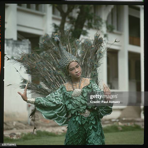 Woman performs the Dance of the Peacock in Bangkok, Thailand. Her costume includes peacock feathers and a headdress in the shape of the bird. This...