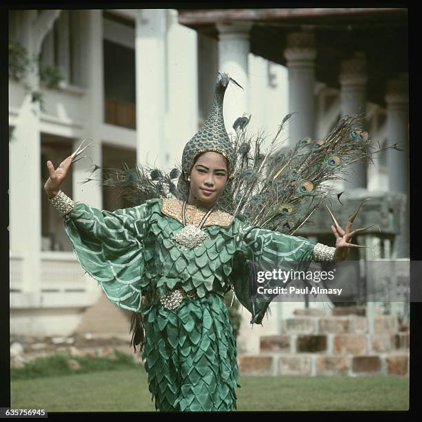 Woman performs the Dance of the Peacock in Bangkok, Thailand. Her costume includes peacock feathers and a headdress in the shape of the bird. This...