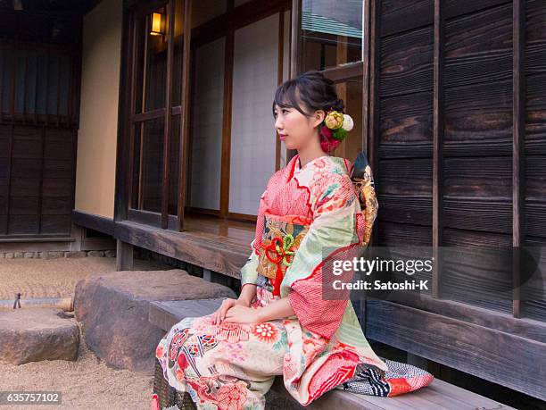 joven furisode mujer sentada en el banco en el jardín de piedra - seijin no hi fotografías e imágenes de stock