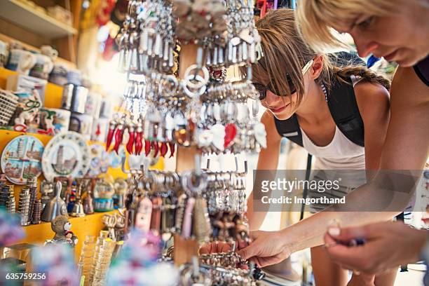 mutter und tochter stöbern souvenirs auf dem straßenmarkt in pisa - souvenirs stock-fotos und bilder