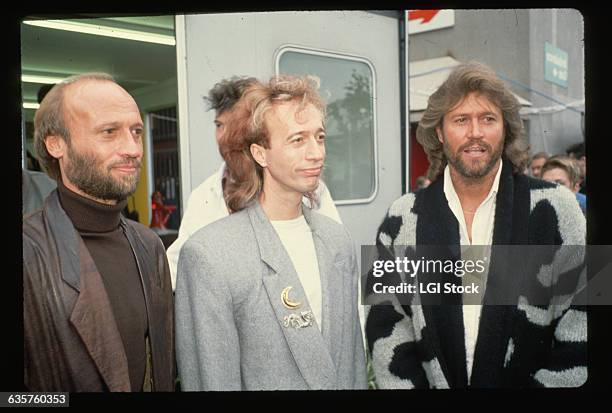 Photo shows the singing group The Bee Gees in a waist-up photo. Left to right: Marice, Robin and Barry Gibb.