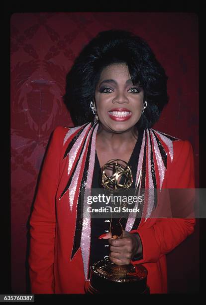 Television talk show host "Oprah Winfrey " smiles while holding an Oscar statuette.