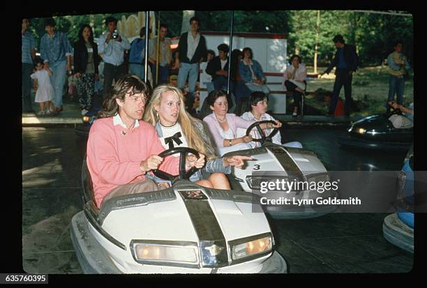 Mick Jagger, singer for the Rolling Stones, and his wife, model Jerry Hall, ride together in a bumper car at an amusement park.