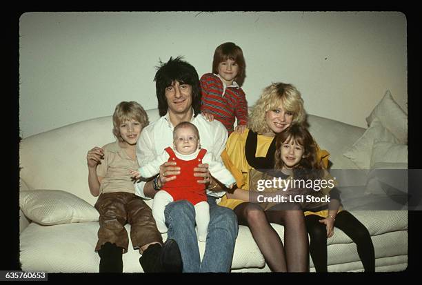 Rolling Stones guitarist Ron Wood sits on a couch with his girlfriend Jo Howard and children.