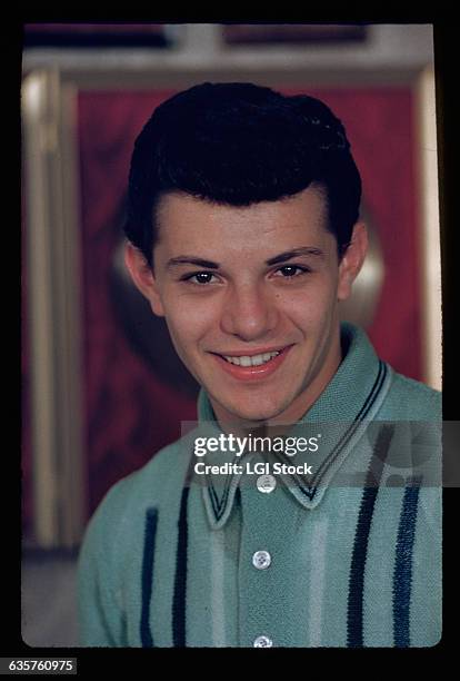 Picture shows actor, Frankie Avalon, as a teenager. He is posing wearing a green and black shirt buttoned to the top. Undated photo circa 1950s.