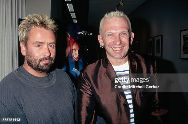 Director Luc Besson and Designer Jean Paul Gaultier at the premier of The Fifth Element with the movie poster in the background exposing actress...