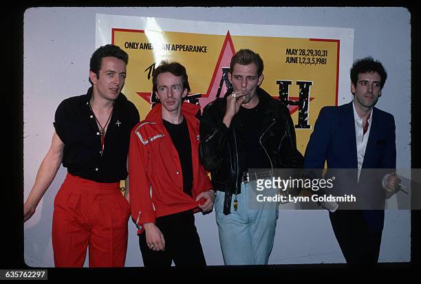 Members of The Clash stands in front of a poster for their tour.