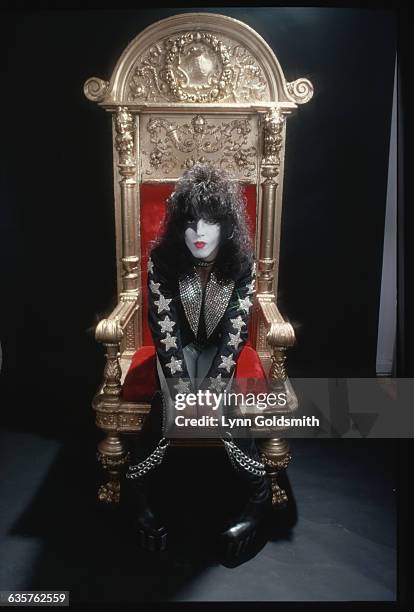 Paul Stanley, lead singer of the group KISS, is shown seated in a throne n this studio portrait.