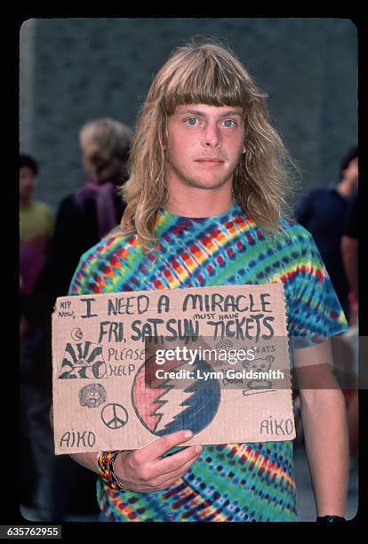 Fan of the band Grateful Dead holds a handmade sign reading I need a miracle, hoping to get tickets to a Grateful Dead show.