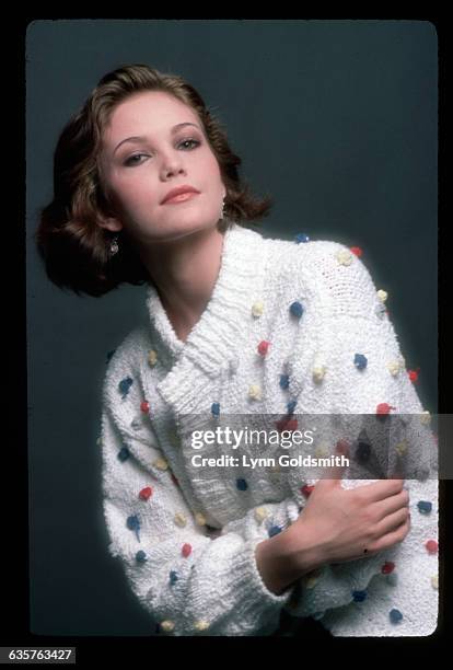 Picture shows actress, Diane Lane, posing in a studio wearing a white sweater with multi-colored balls on it.