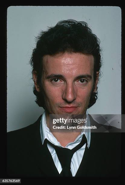 Headshot of rock and roll musician Bruce Springsteen wearing a suit jacket and loose tie showing full face. Photo circa 1978.