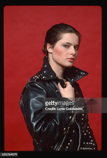 Actress Isabella Rossellini is shown in a studio portrait, wearing a studded leather jacket and her hair slicked back. Undated.