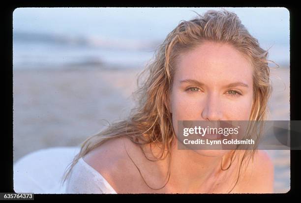 Actress Kelly Lynch is shown on a beach in this head and shoulders photo. She wears a sheer white dress.