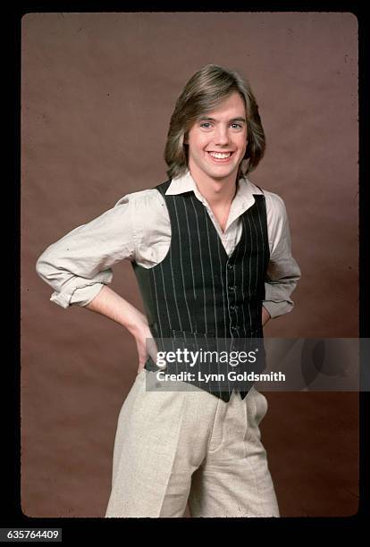 Actor/singer Shaun Cassidy is shown in a 3/4 length studio portrait. His hands are on his hips, and he wears a black vest with pin stripes over...