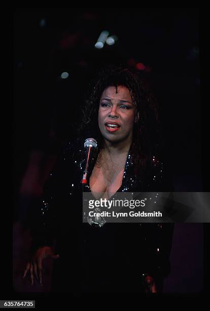 Picture shows jazz and blus singer, Roberta Flack, performing in concert. She is dressed in a black dress with a sequins jacket and large pearl pin.