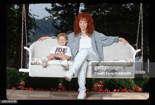 Country singer Reba McEntire and her young son Shelby relax on a porch swing.