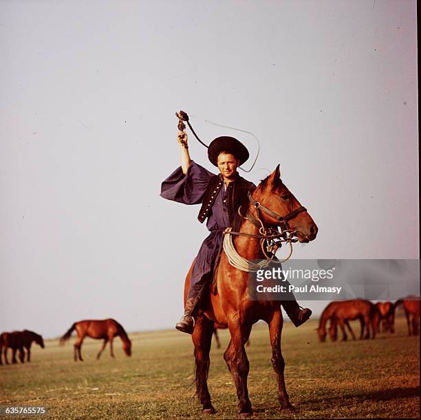 Csikos, or Hungarian cowboy, raises his horse whip.