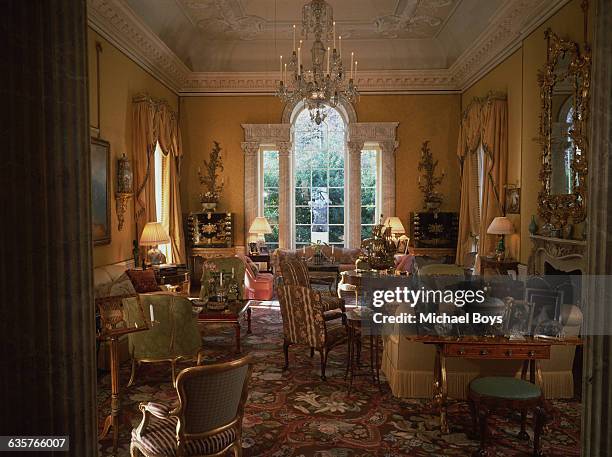 Elegant chairs clustered around tables in a high-ceilinged sitting room.