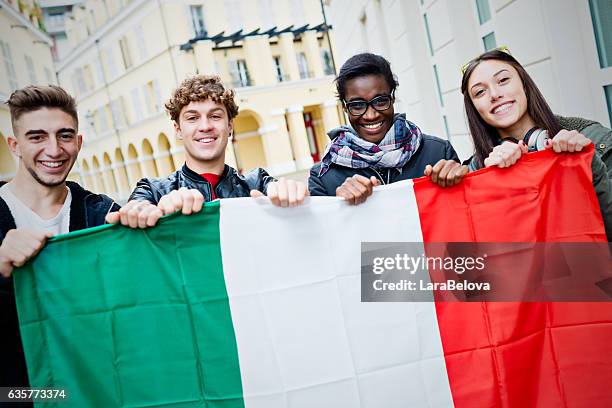 jóvenes amigos mestizos sosteniendo bandera italiana - bandera italiana fotografías e imágenes de stock