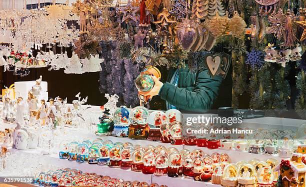 christmas in france salesperson checking on snowball toys on the stand - strasbourg winter stock pictures, royalty-free photos & images