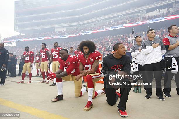 Eli Harold, Colin Kaepernick and Eric Reid of the San Francisco 49ers kneel on the sideline, during the anthem, prior to the game against the New...