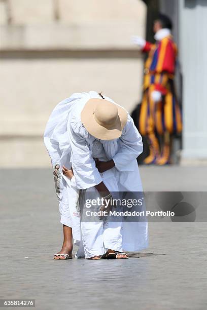 St. Peter's square. Woman from Camerun in white, with a large hat, bending down to reassure her son. They're waiting for the beginning of the General...