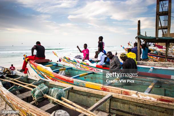 Men stand in the boats on the beach in Saint-Louis.