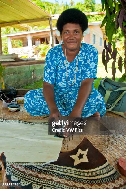 Fijian woman painting design on tapa cloth; Tongo village, Qamea Island, Fiji.