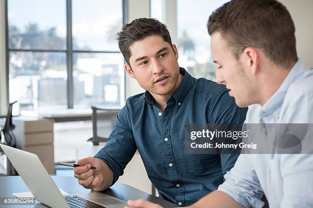 two young businessmen in meeting using laptop - 20s talking serious bildbanksfoton och bilder