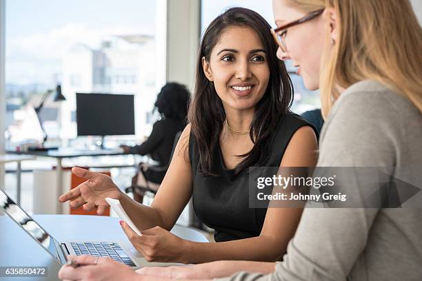 mid adult businesswoman listening to female colleague in office - los angeles events stockfoto's en -beelden