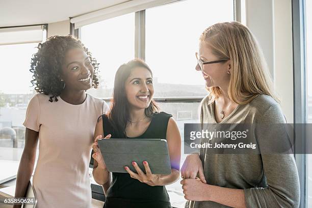 three businesswomen working together using digital tablet - three people portrait stock pictures, royalty-free photos & images