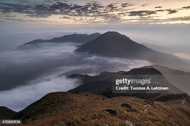 clouds rolling over a mountain on lantau island, viewed from the lantau peak (the 2nd highest peak in hong kong, china) at dawn. - lantau imagens e fotografias de stock