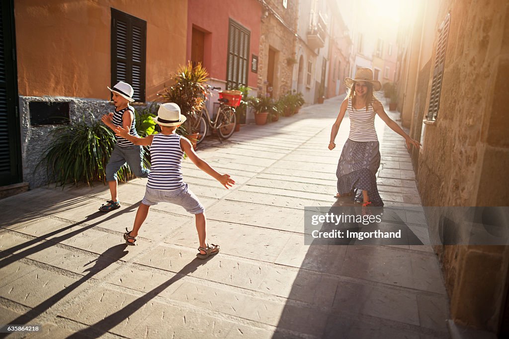 Kids playing tag in mediterranean street.