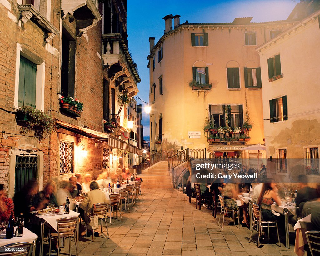 People dining by canal in Venice at dusk