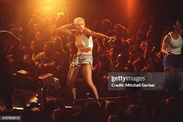 Madonna, wearing short cut off jeans, combat boots, and a tank top cropped to expose her stomach, performs before a crowd at Madison Square Garden.