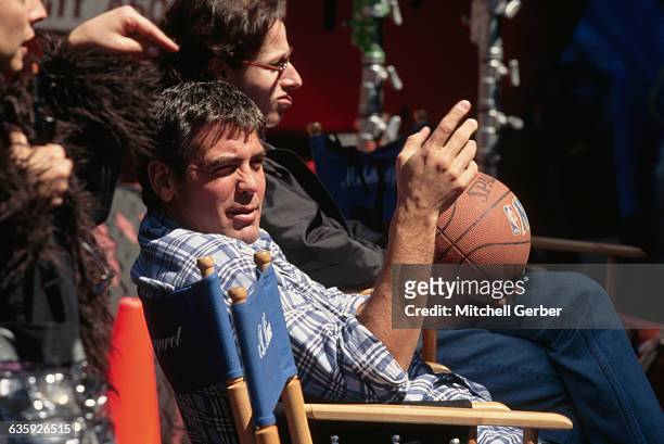 Actor George Clooney holds a basketball sitting on the set of... - Getty Images