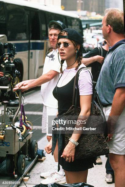 Wearing a backwards baseball cap and sunglasses, actress Jennifer Aniston stands on the set of the motion picture, Picture Perfect, during filming on...