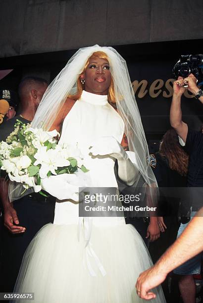 Basketball star and actor Dennis Rodman, dressed as a bride, is surrounded by photographers in Rockefeller Center.