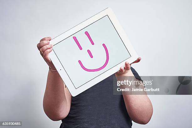 child holding a tablet with a face drawn on - newnaivetytrend ストックフォトと画像