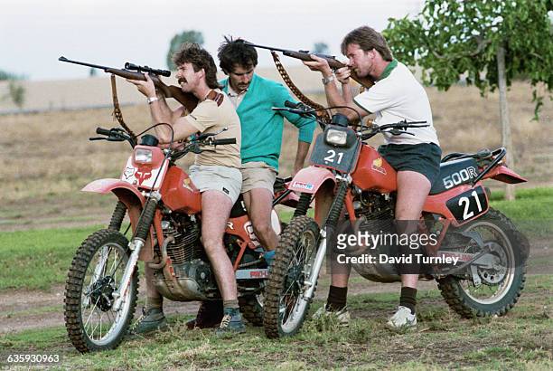 Men Aiming Rifles on Motorcycles