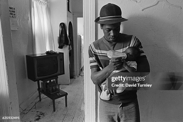 Father feeds his baby in his home in Detroit's Poletown neighborhood. The ethnically-diverse, working class neighborhood is being razed to make room...