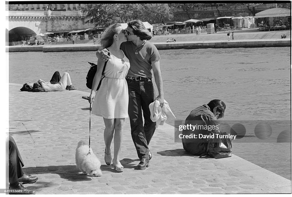 Couple Kissing While Walking Their Dog