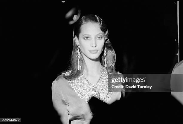 Super model Christy Turlington strolls off stage wearing huge earrings and jeweled collar.